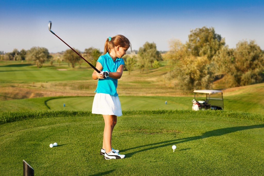 A young girl playing golf on the field