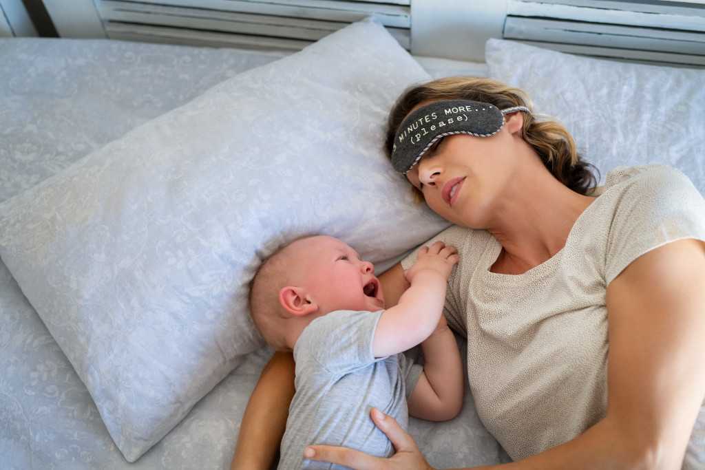 mom sleeping next to a crying baby