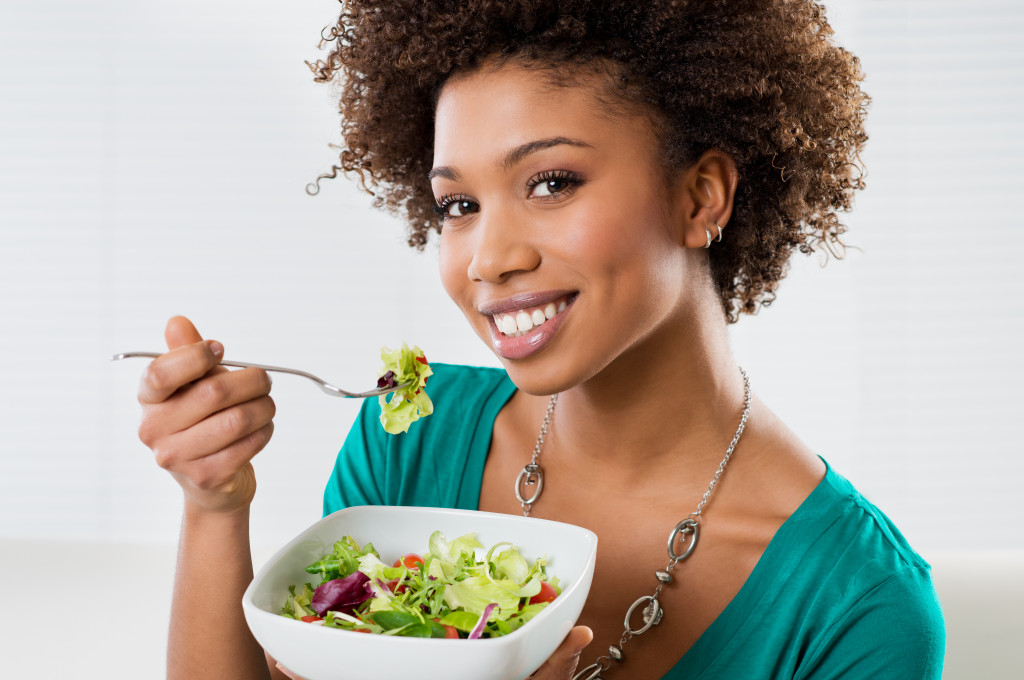 Young woman eating salad from a bowl at home.