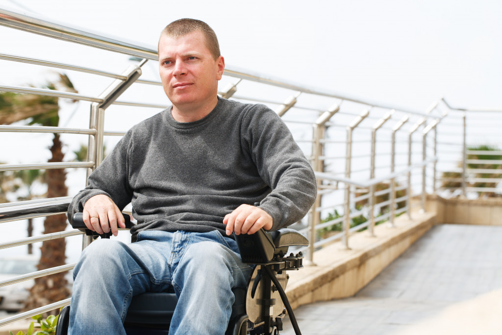 Man in a wheelchair sitting along a railing of a building.