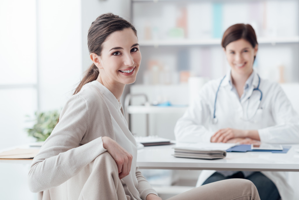 woman smiling looking back with female doctor smiling behind her in her desk