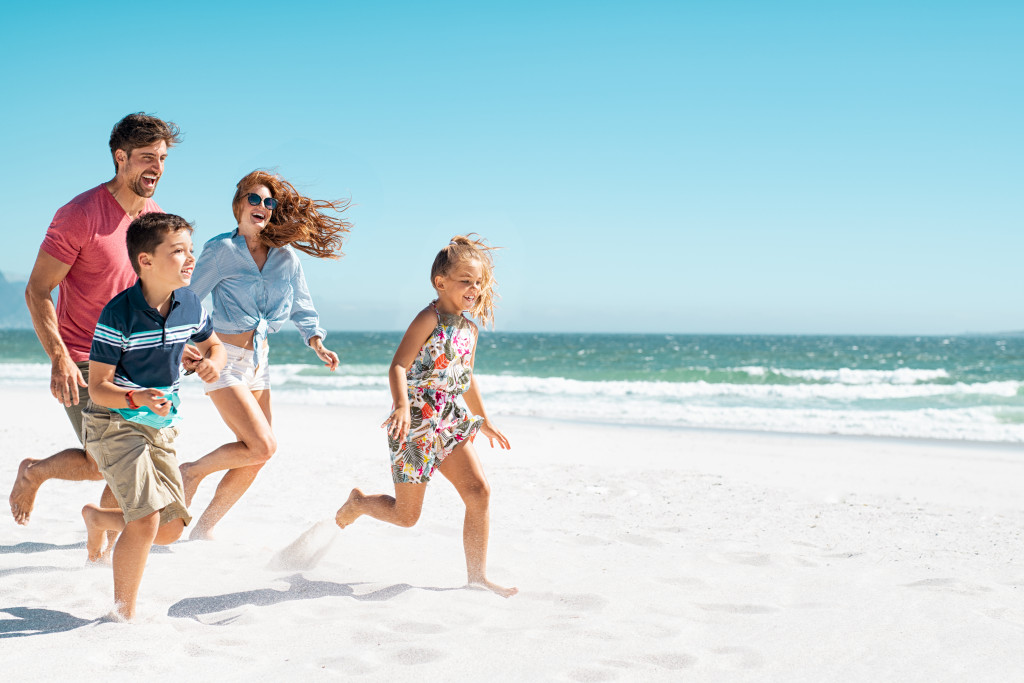 Young children running in the beach with their parents.
