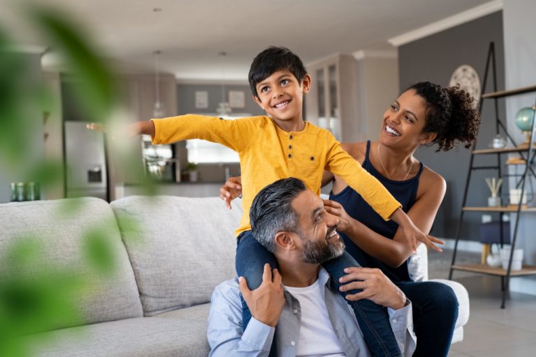 young boy carried by father and mother on the side in living room